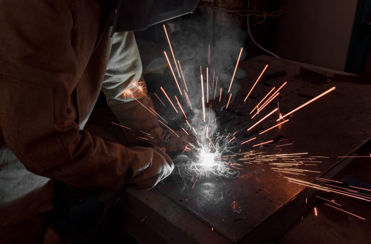 cropped image of welder in protection mask working with metal at factory